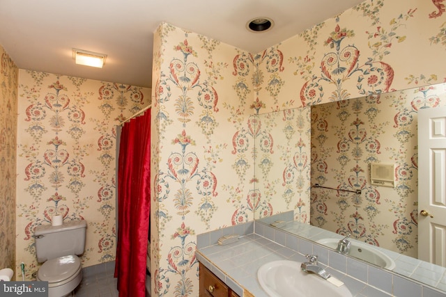 bathroom with toilet, vanity, and tile patterned flooring