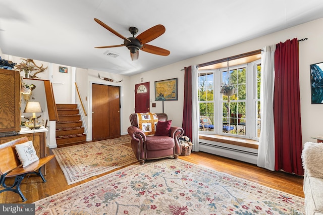 living area featuring ceiling fan, a baseboard heating unit, and light hardwood / wood-style flooring