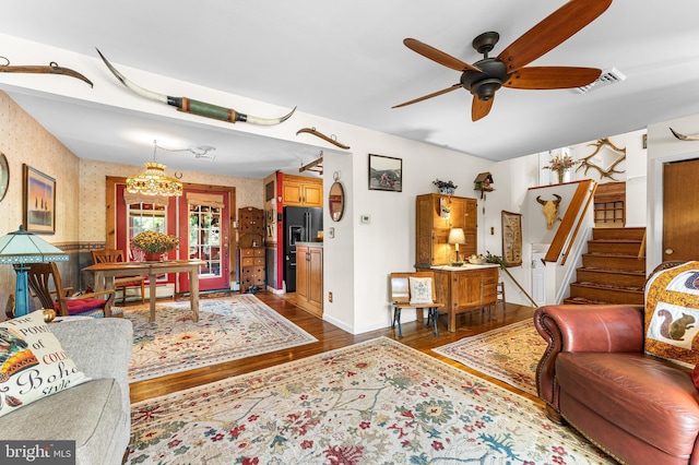 living room with ceiling fan with notable chandelier and hardwood / wood-style flooring