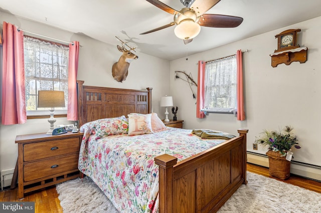 bedroom with ceiling fan, multiple windows, and wood-type flooring