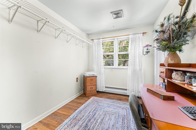 walk in closet featuring hardwood / wood-style flooring and a baseboard radiator