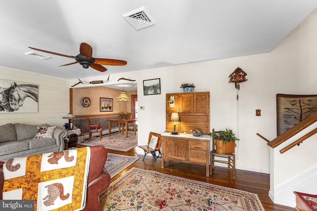 living room with ceiling fan, dark hardwood / wood-style floors, and wooden walls