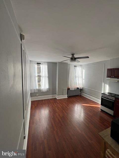 unfurnished living room with radiator, dark wood-type flooring, a healthy amount of sunlight, and ceiling fan