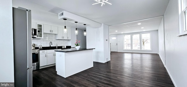 kitchen featuring pendant lighting, white cabinets, a center island, dark wood-type flooring, and stainless steel appliances