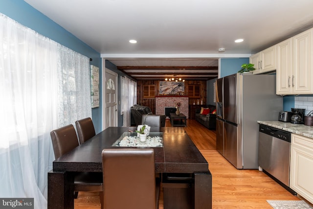 862 Bay Ave, Toms River, NJ 08753 - dining room with beamed ceiling, a wealth of natural light, a fireplace, and light hardwood / wood-style flooring