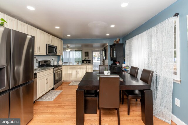 862 Bay Ave, Toms River, NJ 08753 - kitchen featuring appliances with stainless steel finishes, backsplash, light stone counters, kitchen peninsula, and light wood-type flooring