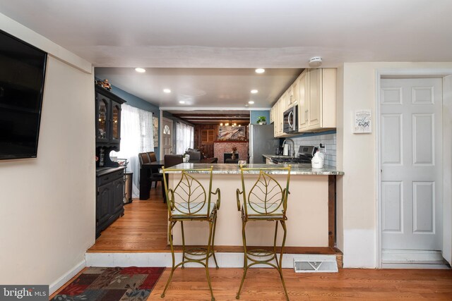 862 Bay Ave, Toms River, NJ 08753 - kitchen featuring light hardwood / wood-style flooring, a breakfast bar area, appliances with stainless steel finishes, decorative backsplash, and kitchen peninsula