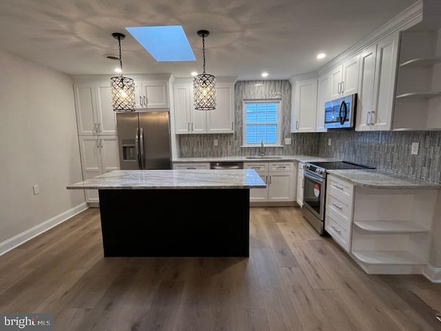 kitchen with decorative light fixtures, a center island, white cabinetry, a skylight, and appliances with stainless steel finishes