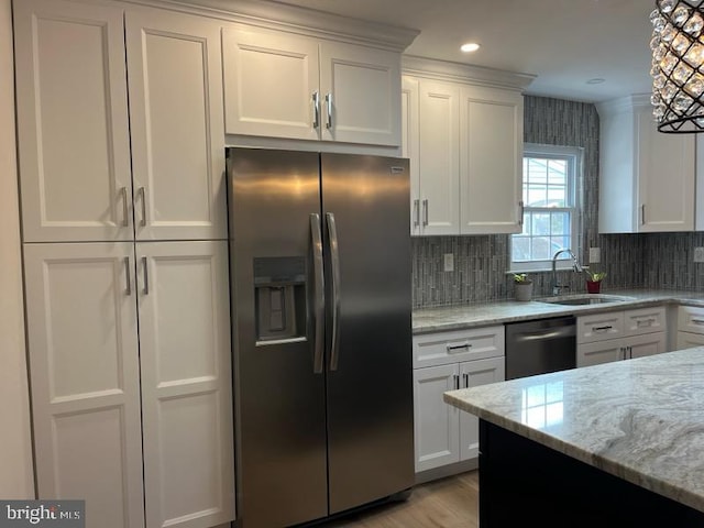 kitchen with light stone countertops, white cabinets, appliances with stainless steel finishes, and sink