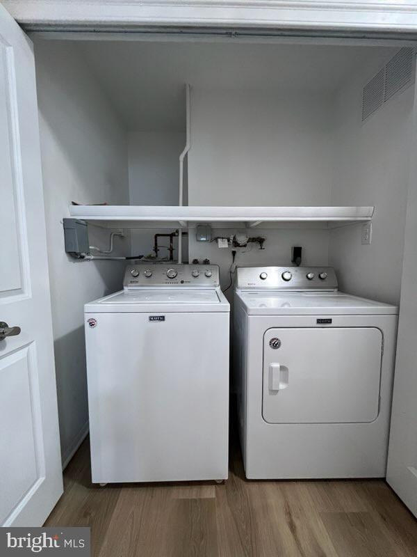 laundry room with separate washer and dryer and wood-type flooring