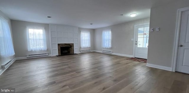 unfurnished living room with hardwood / wood-style floors, a fireplace, and a baseboard radiator