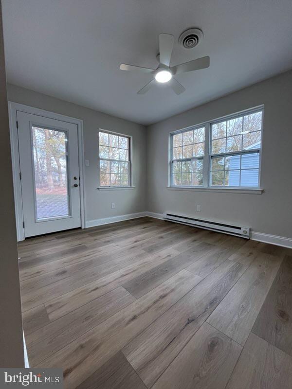 empty room featuring light wood-type flooring, baseboard heating, and ceiling fan