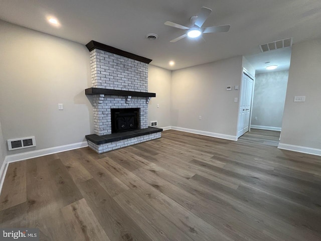 unfurnished living room featuring a brick fireplace, wood-type flooring, and ceiling fan