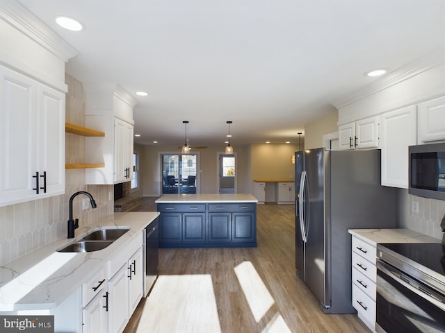 kitchen with sink, light stone counters, pendant lighting, stainless steel appliances, and white cabinets