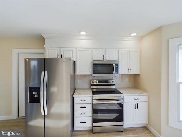 kitchen featuring white cabinetry, backsplash, light hardwood / wood-style flooring, and stainless steel appliances