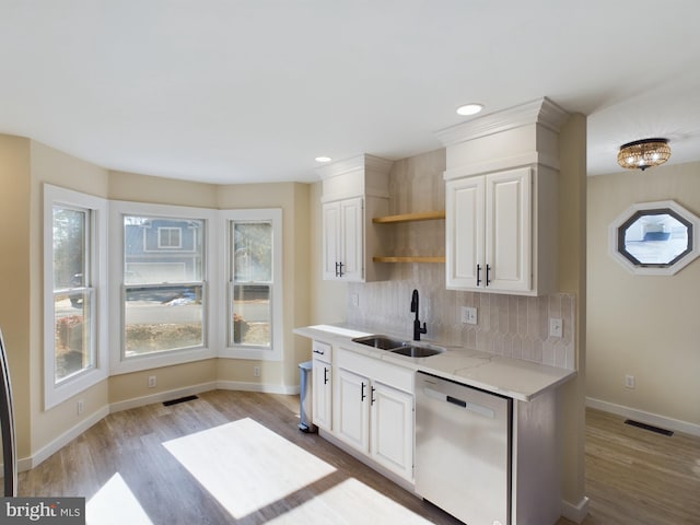 kitchen featuring backsplash, stainless steel dishwasher, sink, light wood-type flooring, and white cabinets