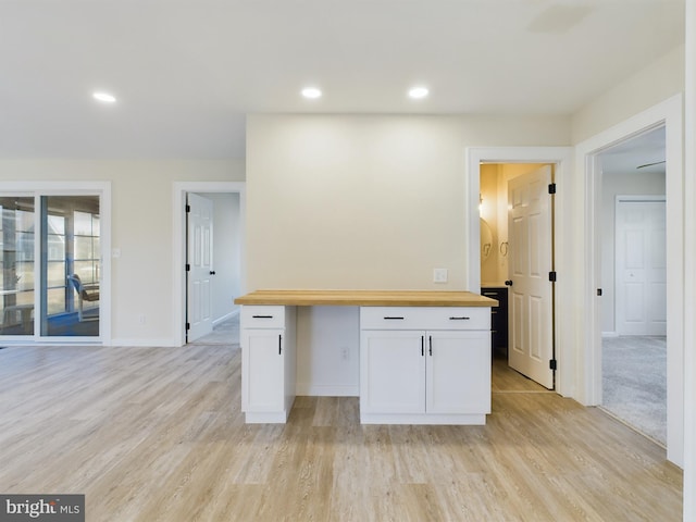 kitchen with light hardwood / wood-style floors, white cabinets, and butcher block counters