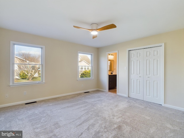 unfurnished bedroom featuring ceiling fan, connected bathroom, a closet, and light carpet