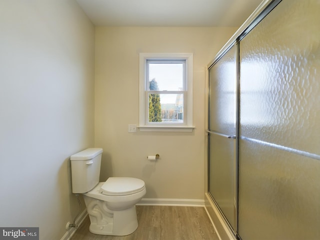 bathroom featuring toilet, a shower with shower door, and hardwood / wood-style floors