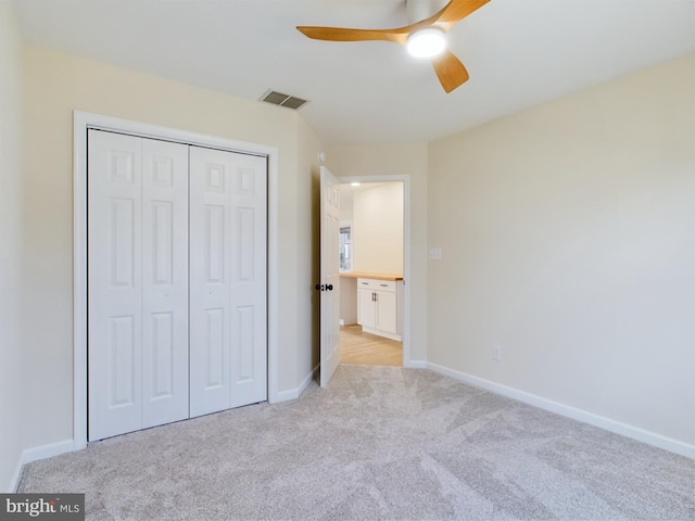 unfurnished bedroom with a closet, light colored carpet, and ceiling fan