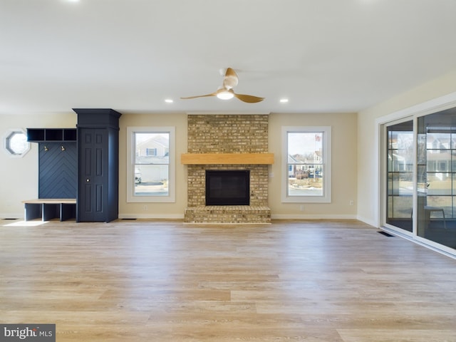 unfurnished living room featuring a fireplace, ceiling fan, and light hardwood / wood-style floors