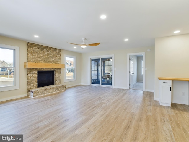 unfurnished living room with a fireplace, light hardwood / wood-style floors, plenty of natural light, and ceiling fan