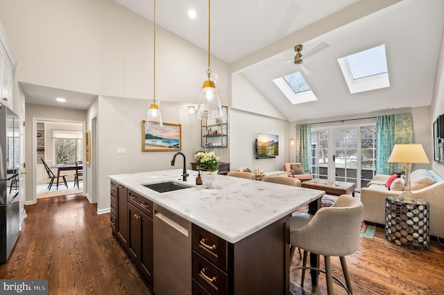 kitchen featuring sink, decorative light fixtures, dark brown cabinets, dishwasher, and an island with sink