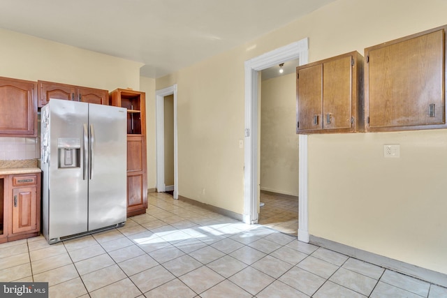 kitchen with stainless steel fridge with ice dispenser, backsplash, and light tile patterned flooring