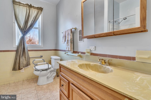 bathroom featuring toilet, vanity, tile patterned floors, and tile walls