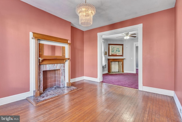 unfurnished living room featuring hardwood / wood-style flooring and ceiling fan with notable chandelier