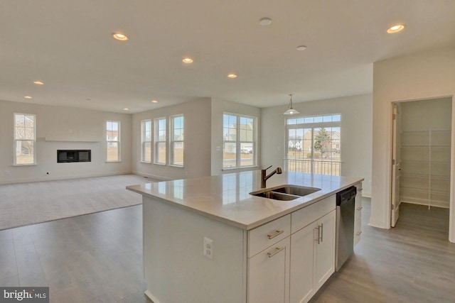 kitchen featuring white cabinetry, an island with sink, decorative light fixtures, stainless steel dishwasher, and sink