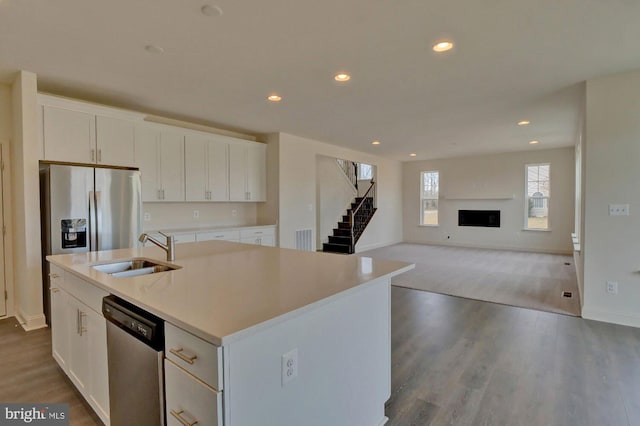 kitchen with sink, white cabinets, appliances with stainless steel finishes, and a kitchen island with sink