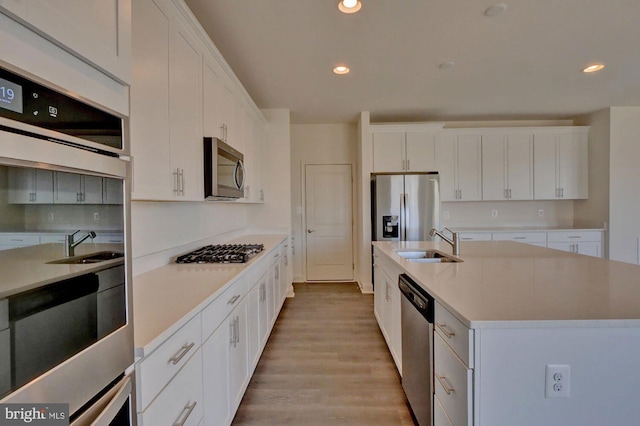 kitchen featuring white cabinets, sink, appliances with stainless steel finishes, and an island with sink