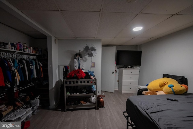 bedroom featuring wood-type flooring, a paneled ceiling, and a closet