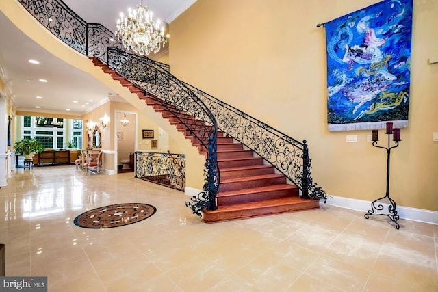 staircase with ornamental molding, a towering ceiling, and a chandelier