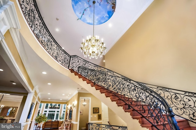 stairs featuring a notable chandelier, ornamental molding, and a high ceiling