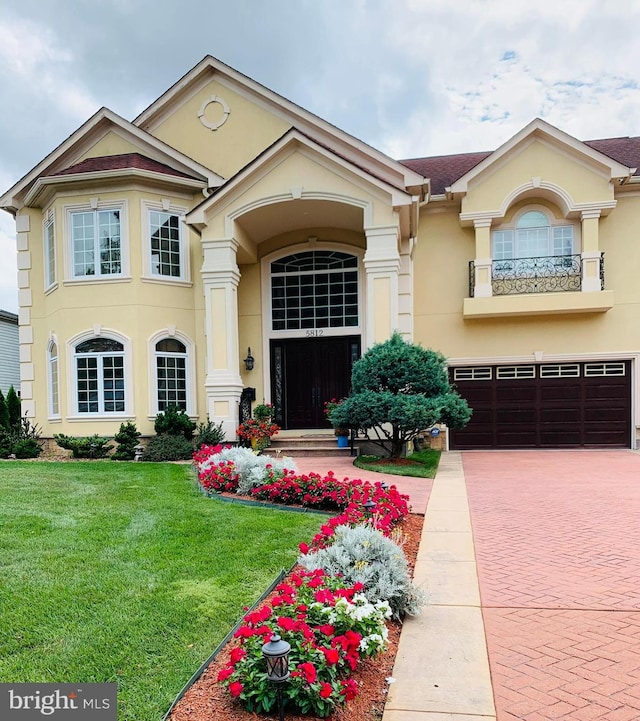 view of front facade featuring a balcony, a garage, and a front lawn