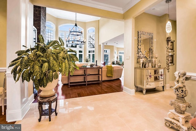 entrance foyer with ornate columns, crown molding, and a chandelier