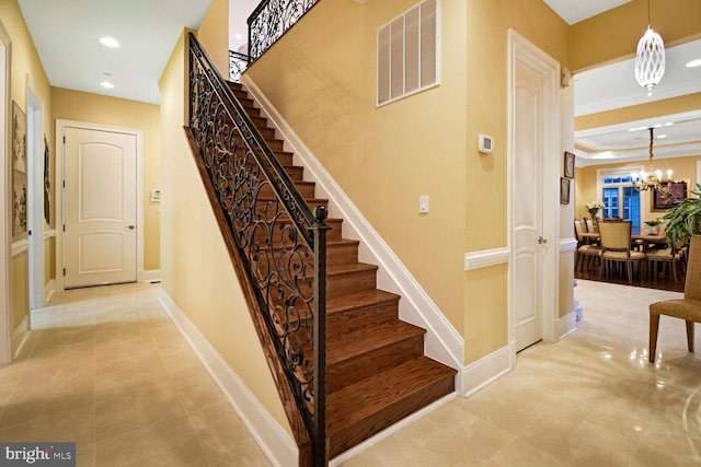 staircase with ornamental molding and a notable chandelier