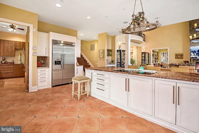 kitchen featuring black electric stovetop, white cabinets, stainless steel built in fridge, and light tile patterned flooring