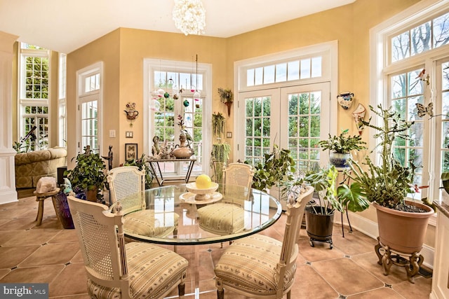 sunroom featuring a notable chandelier, plenty of natural light, and french doors