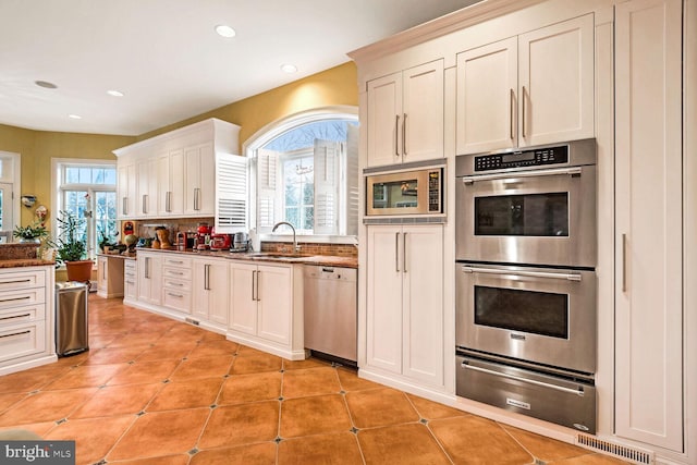 kitchen featuring white cabinetry, appliances with stainless steel finishes, sink, and light tile patterned flooring