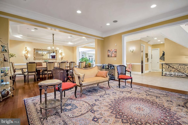 living room featuring crown molding, wood-type flooring, a raised ceiling, and an inviting chandelier