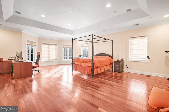 bedroom featuring ornamental molding, a tray ceiling, and light wood-type flooring