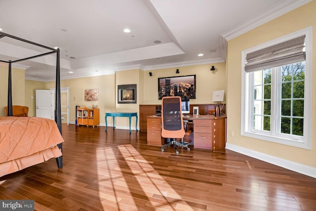 bedroom featuring crown molding, hardwood / wood-style flooring, and a tray ceiling