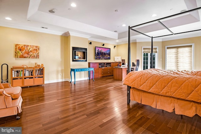 bedroom with a raised ceiling, ornamental molding, and hardwood / wood-style flooring