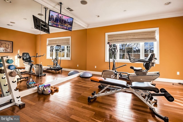 exercise room with hardwood / wood-style floors, ornamental molding, and a wealth of natural light