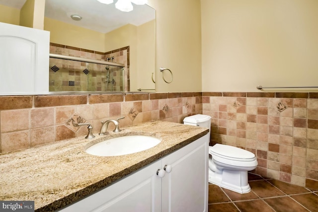 bathroom with tile walls, vanity, tile patterned floors, toilet, and walk in shower