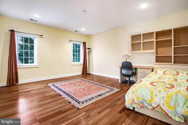 bedroom featuring built in desk and hardwood / wood-style floors