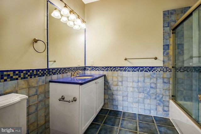 full bathroom featuring shower / bath combination with glass door, tile patterned flooring, tile walls, vanity, and toilet